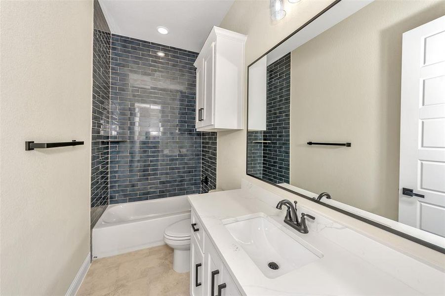 Full bathroom with tile patterned flooring, toilet, vanity, and tiled shower / bath