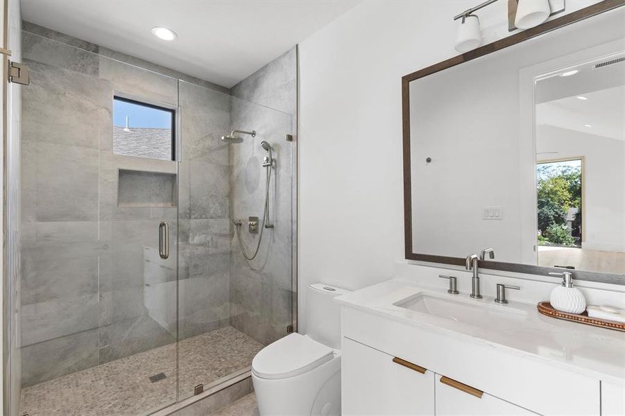 Bathroom featuring walk in shower, vanity, plenty of natural light, and toilet