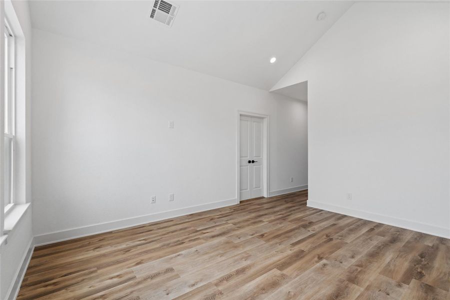 Large primary bedroom with high ceilings and plenty of room for a full bedroom setup.