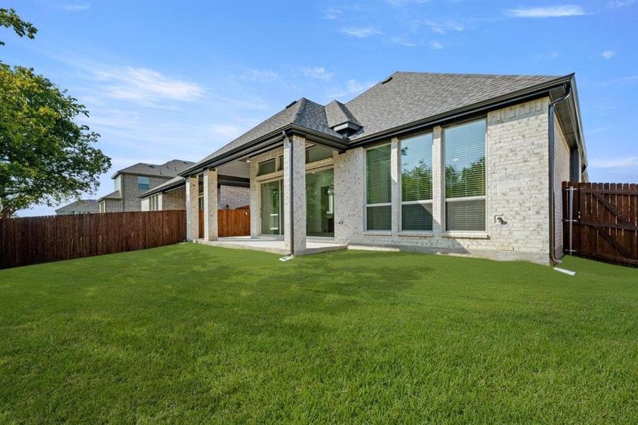 Rear view of house featuring a patio area, a fenced backyard, brick siding, and a shingled roof