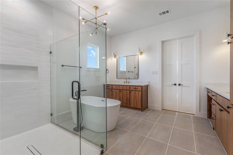 Bathroom featuring shower with separate bathtub, tile patterned flooring, vanity, and an inviting chandelier