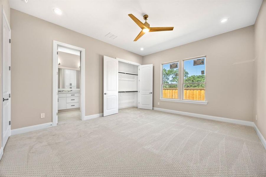 bedroom with ceiling fan, light carpet, and ensuite bathroom