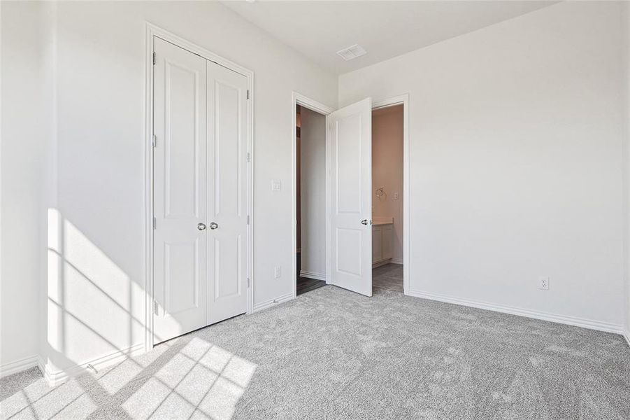 Unfurnished bedroom with light carpet and a closet