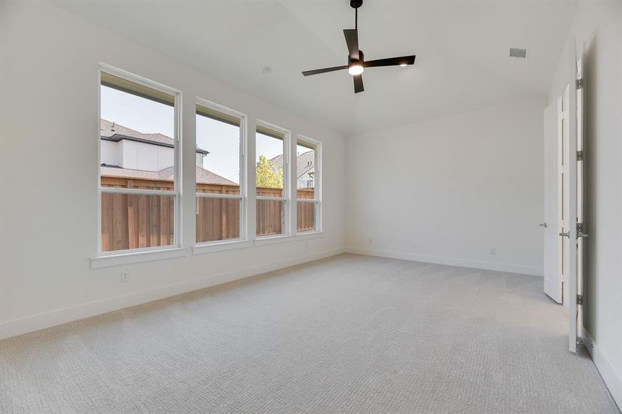 Unfurnished room featuring lofted ceiling, light carpet, and a ceiling fan