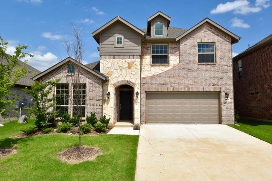 View of front of home with brick siding, an attached garage, a front yard, and concrete driveway