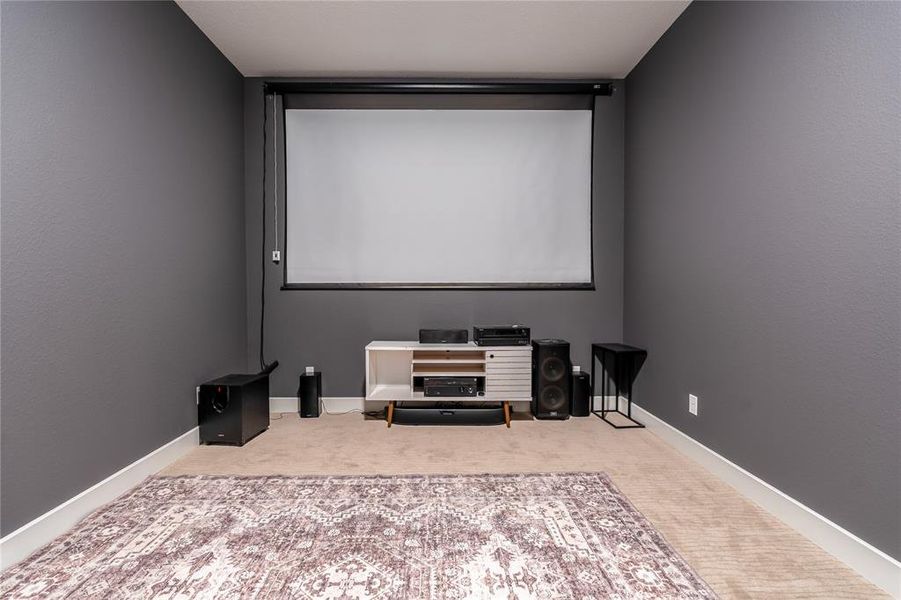 Cinema featuring a textured ceiling and light carpet