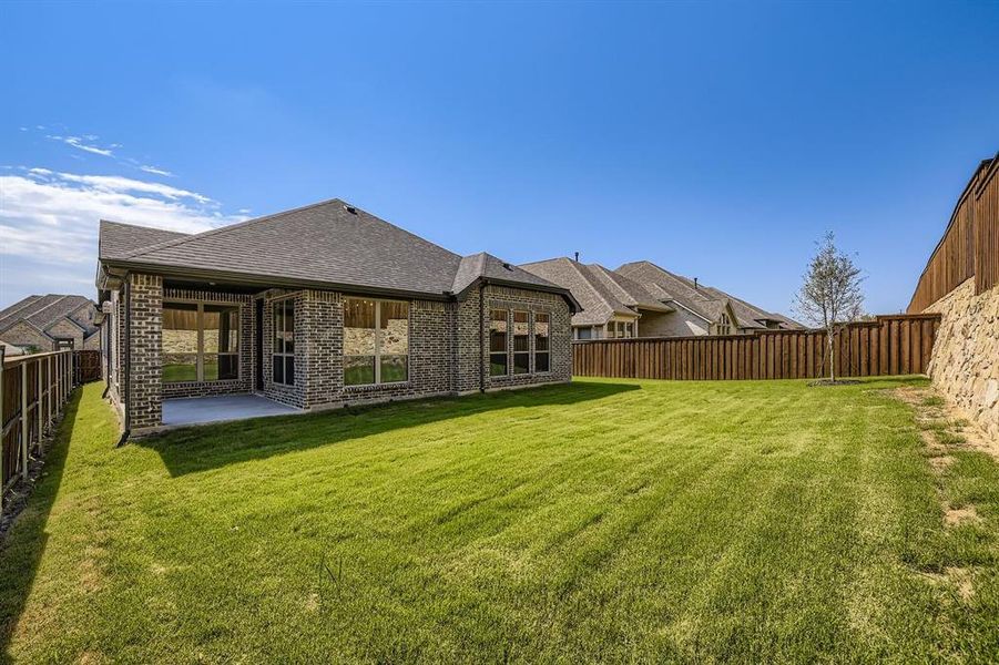 Rear view of property featuring brick siding, a fenced backyard, a patio, and a shingled roof