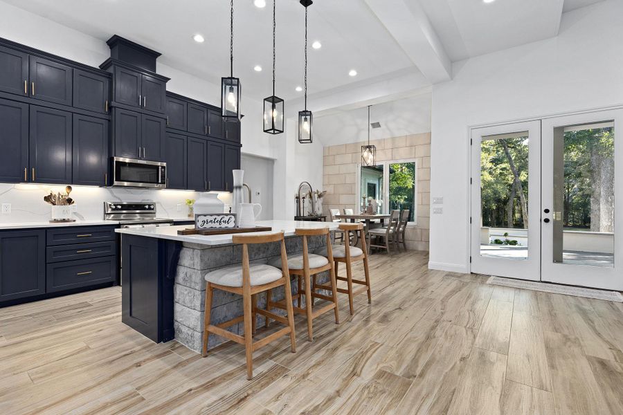 Kitchen with a kitchen island with sink, beamed ceiling, hanging light fixtures, decorative backsplash, and a breakfast bar area Kitchen with a kitchen island with sink, beamed ceiling, hanging light fixtures, decorative backsplash, and a breakfast bar area