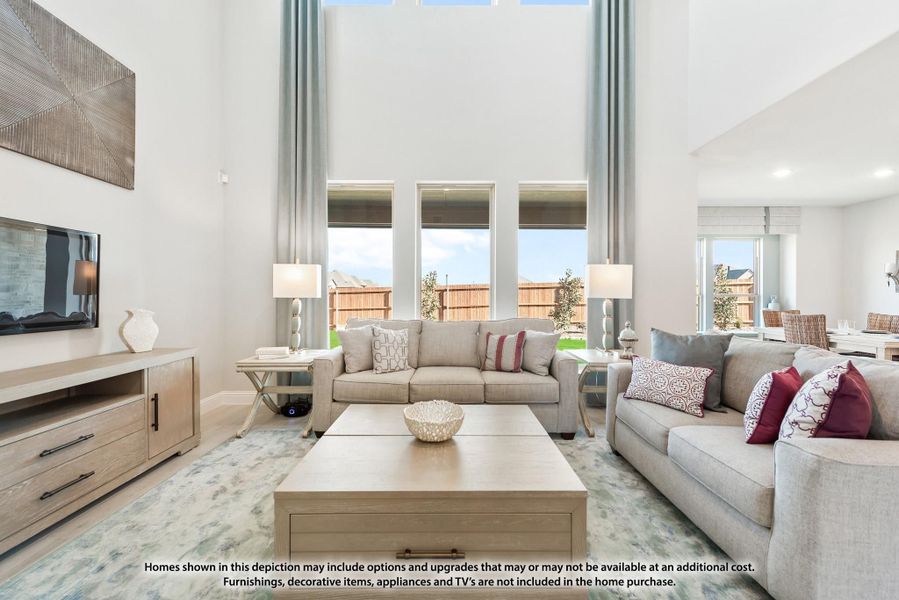 Living room with two-story ceiling, large windows, two gray sofas, and a wood coffee table