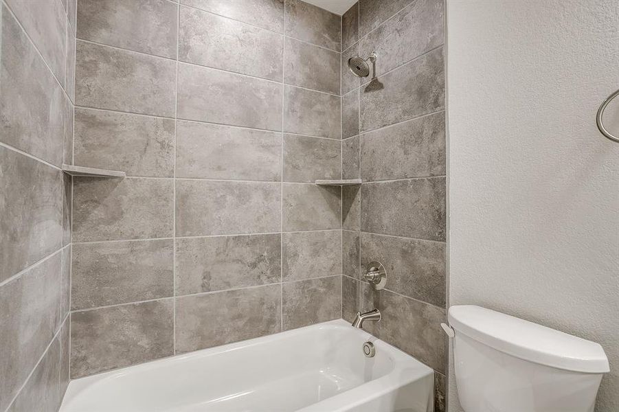 Bathroom with a textured wall and shower / bath combination