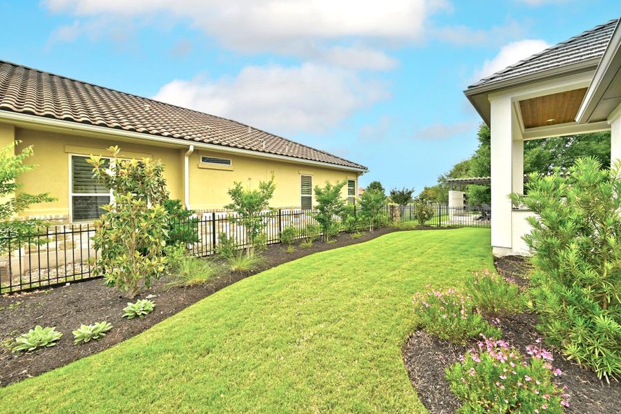 Expansive lawn with mature landscaping and decorative fencing