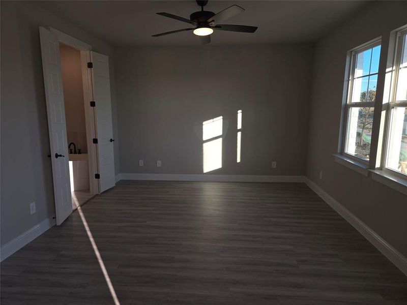 Spare room featuring dark hardwood / wood-style floors, ceiling fan, and a wealth of natural light