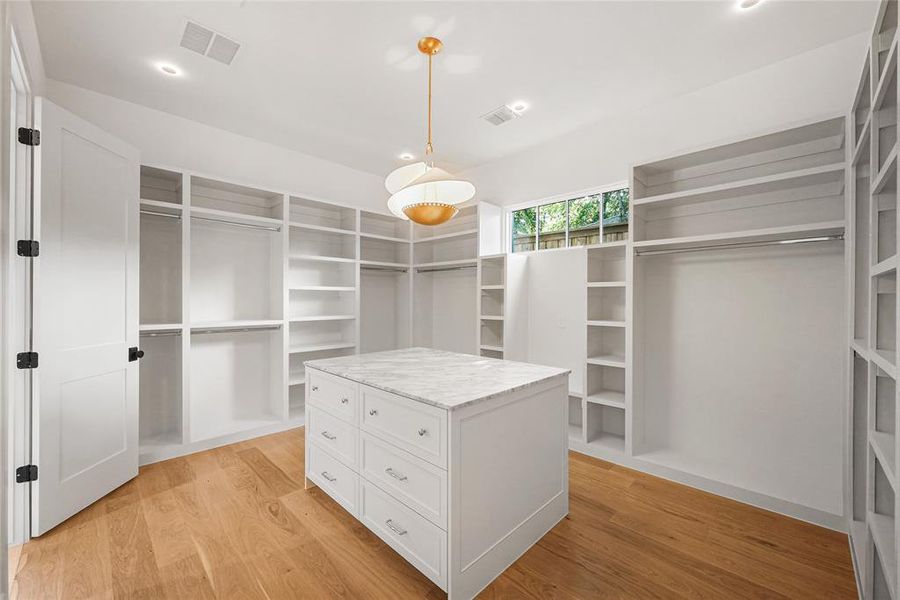 Custom closet system featuring a central island with a stone countertop and drawers