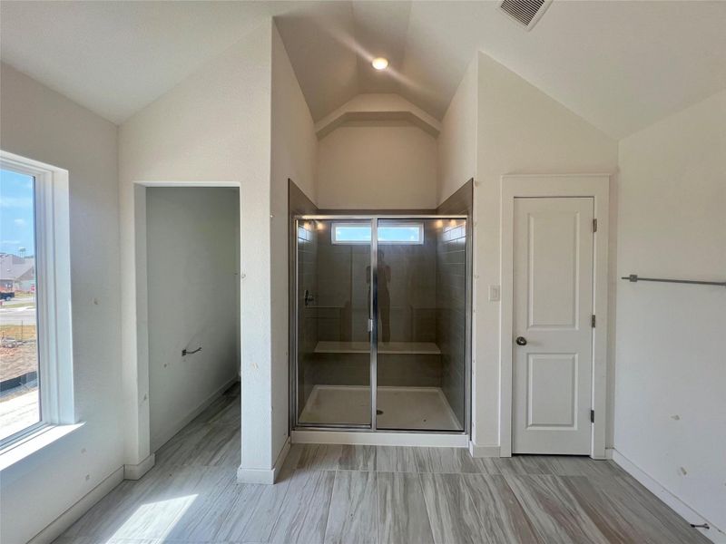 Full bathroom with vaulted ceiling and a stall shower
