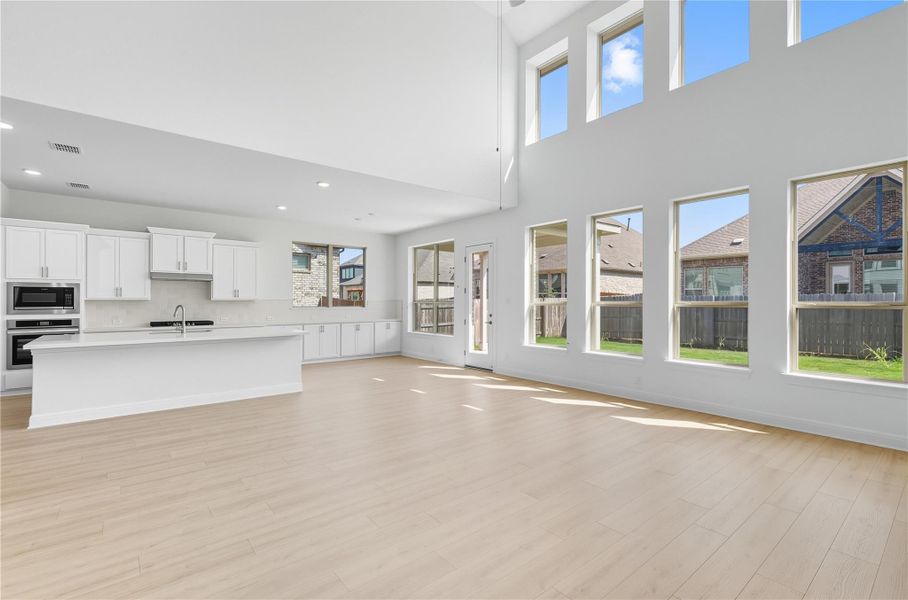 Unfurnished living room featuring light wood-style flooring, a high ceiling, and recessed lighting