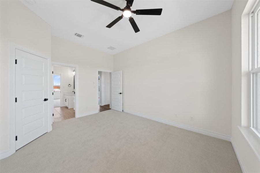Unfurnished bedroom featuring light carpet, connected bathroom, and a ceiling fan Unfurnished bedroom featuring light carpet, connected bathroom, and a ceiling fan