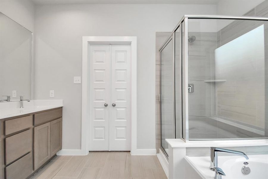 Delight in a spacious walk-in shower enveloped in stylish tile surround, unwind in a separate garden tub adorned with custom detailing, and elevate your daily routine at the elegant vanity, now equipped with double sinks, light countertops, modern hardware. Photo shown is example of completed home with similar plan. Actual colors and selections may vary.