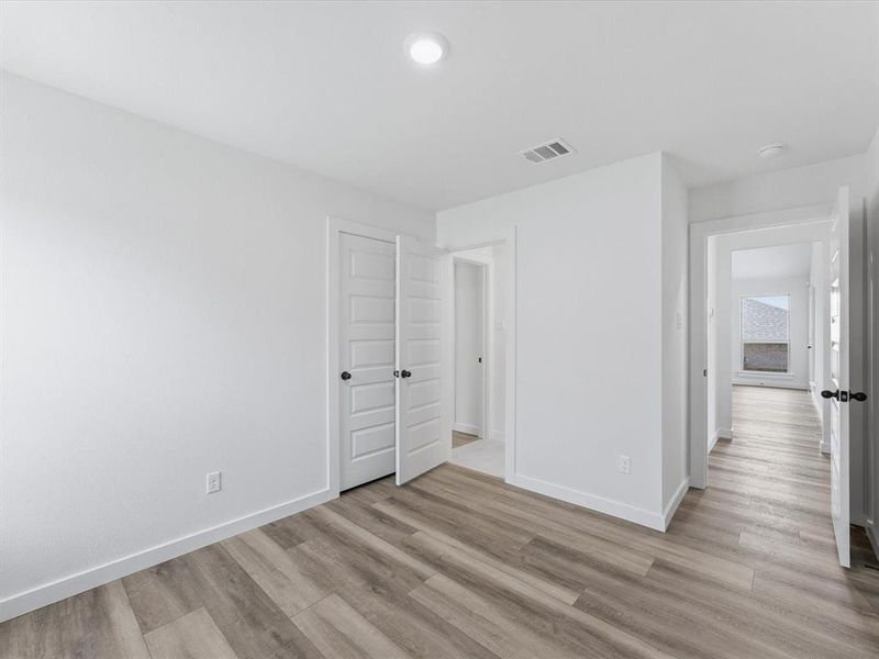 Bright interior space featuring wood-finish flooring, white baseboards, and white walls Bright interior space featuring wood-finish flooring, white baseboards, and white walls