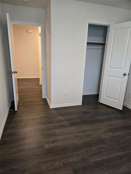 Unfurnished bedroom with dark hardwood / wood-style floors and a closet