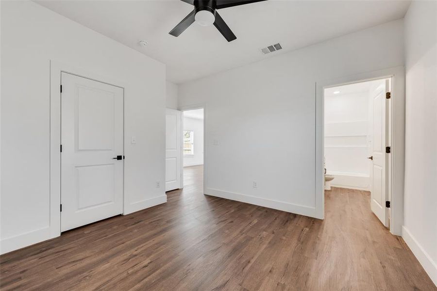 Unfurnished bedroom featuring dark wood-style flooring, ceiling fan, and ensuite bath Unfurnished bedroom featuring dark wood-style flooring, ceiling fan, and ensuite bath