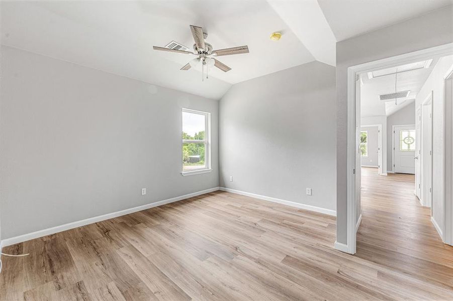 Empty room featuring attic access, lofted ceiling, a ceiling fan, baseboards, and light wood finished floors Empty room featuring attic access, lofted ceiling, a ceiling fan, baseboards, and light wood finished floors