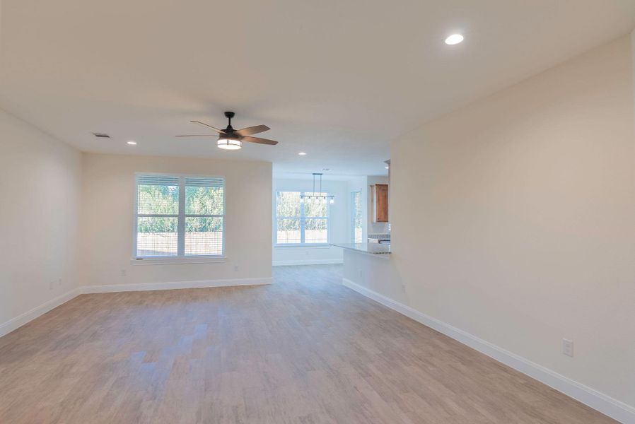 Unfurnished living room featuring light wood finished floors, recessed lighting, ceiling fan, and a chandelier Unfurnished living room featuring light wood finished floors, recessed lighting, ceiling fan, and a chandelier