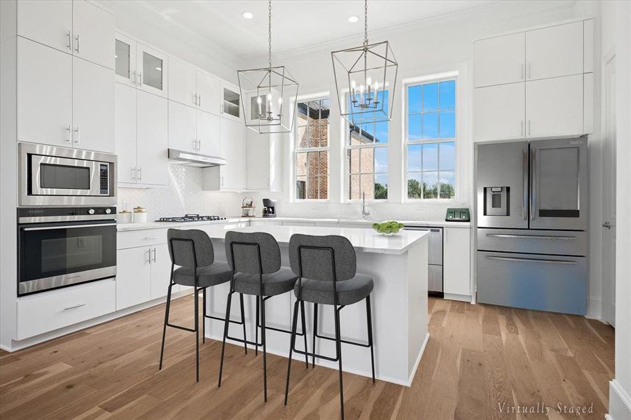 Kitchen with white cabinetry, a breakfast bar area, stainless steel appliances, ornamental molding, and recessed lighting Kitchen with white cabinetry, a breakfast bar area, stainless steel appliances, ornamental molding, and recessed lighting