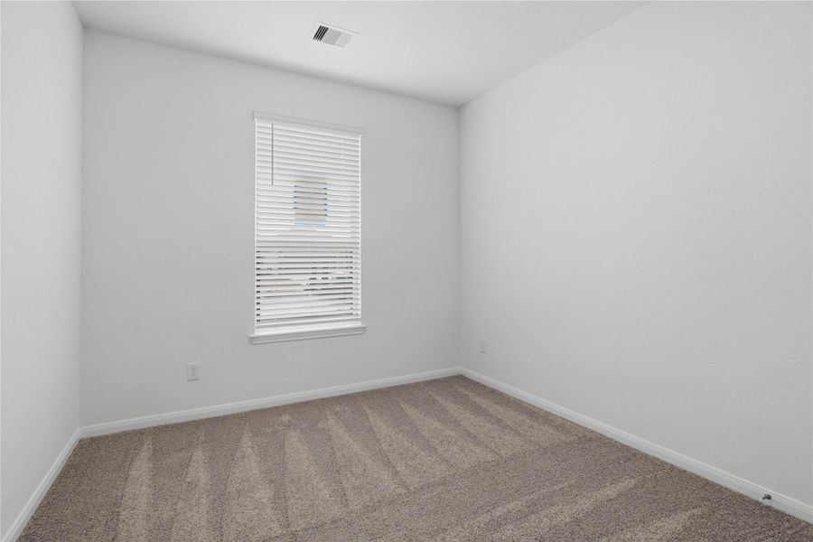 Tucked peacefully in the front of the home is this secondary bedroom. It features plush carpet flooring, a large window, and an ample sized closet space.