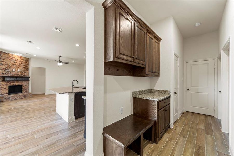 Kitchen featuring wood finish floors, open floor plan, light stone countertops, a brick fireplace, and recessed lighting Kitchen featuring wood finish floors, open floor plan, light stone countertops, a brick fireplace, and recessed lighting