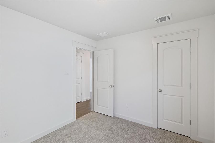 Unfurnished bedroom featuring light colored carpet and baseboards
