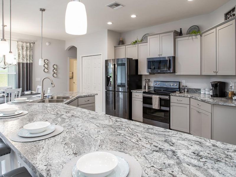 The open kitchen includes a counter-height island and ample cabinet and counter space - Willow II by Highland Homes