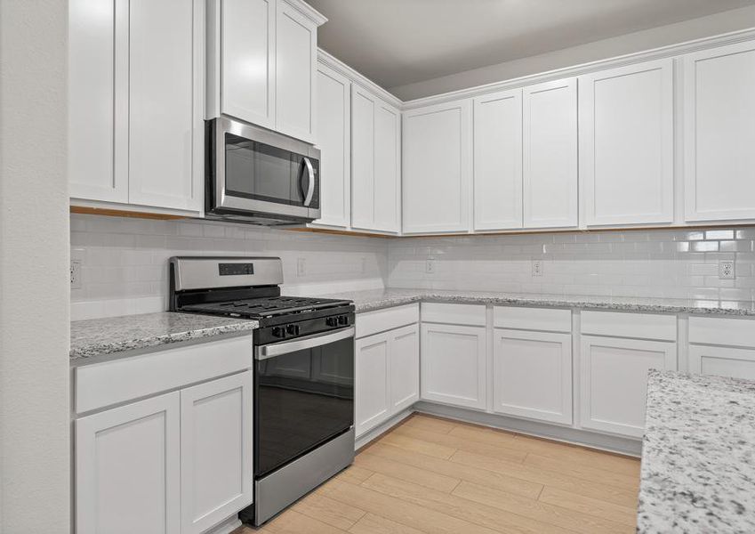 The kitchen of the Willow has white wood cabinets.