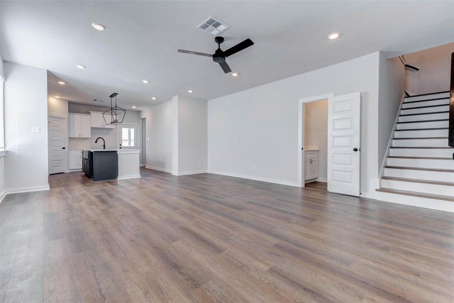 From this angle, you’ll appreciate the home’s main level flow where the kitchen, living, and stairwell connect with thoughtful functionality. Recessed lighting, fresh white walls, and warm-toned flooring give you a blank canvas ready for life and style.
