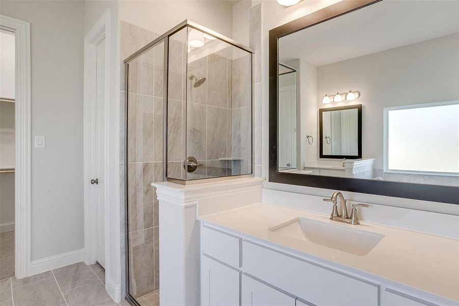 Bathroom featuring tile patterned flooring, a shower with door, and vanity