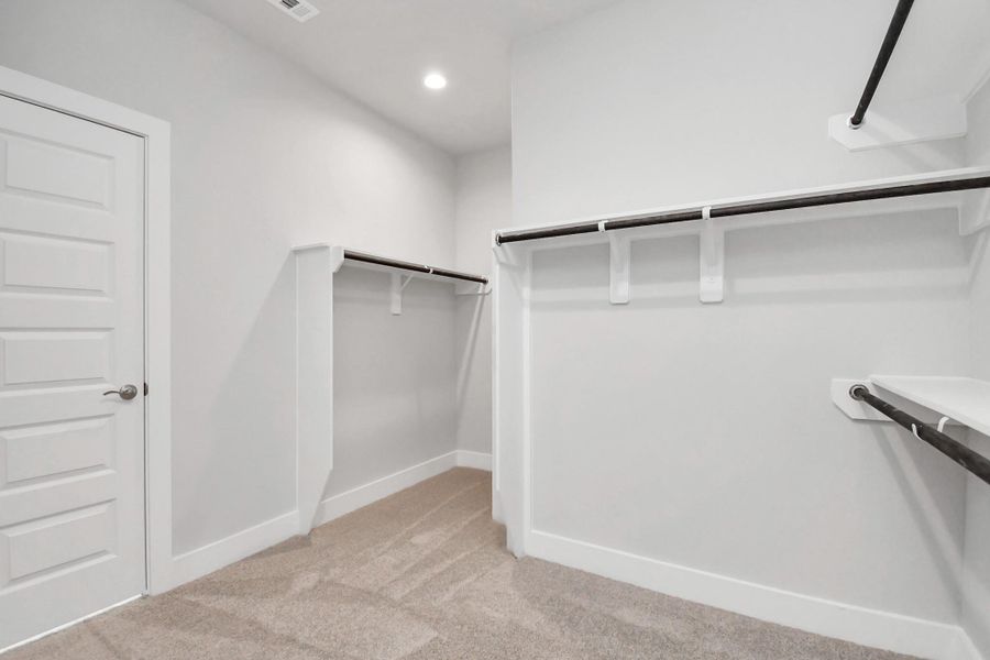 Step into a walk-in closet that defines luxury and functionality. This generously sized space boasts built-in shelving, providing ample room for organization. Sample photo of completed home with similar floor plan. Actual colors and selections may vary.