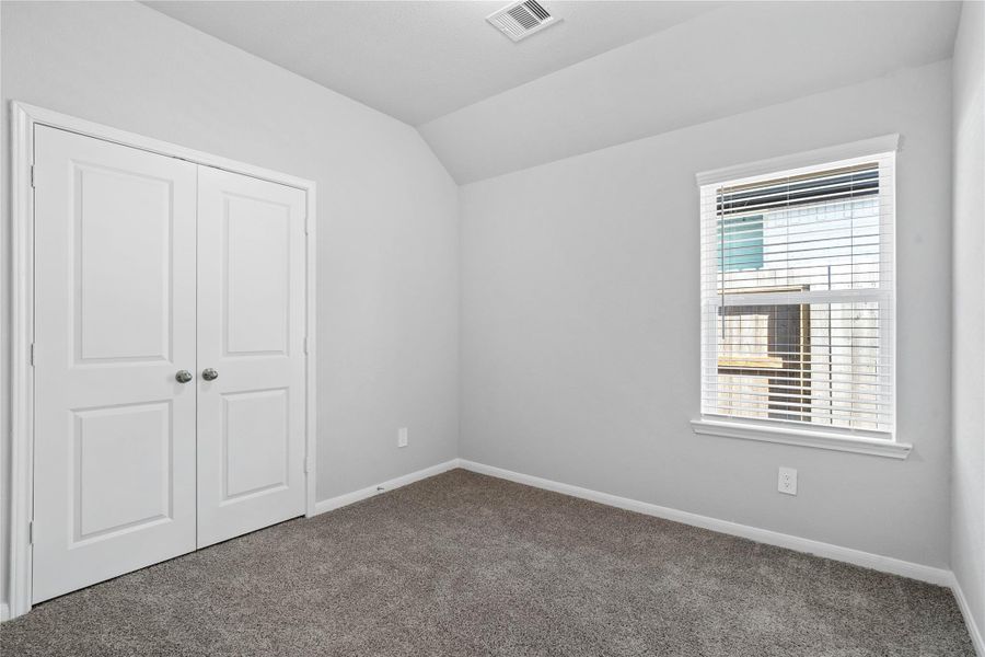 Perfect for guests or a quiet home office, this room features soft plush carpeting, a window with fitted blinds, sloped ceiling, and ample sized closet space.