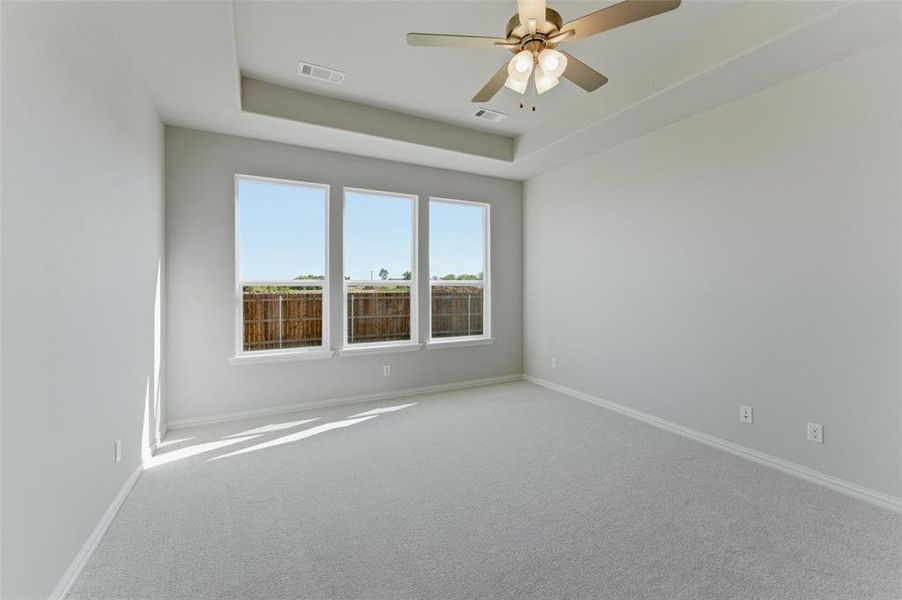 Spare room featuring carpet floors, ceiling fan, and a tray ceiling