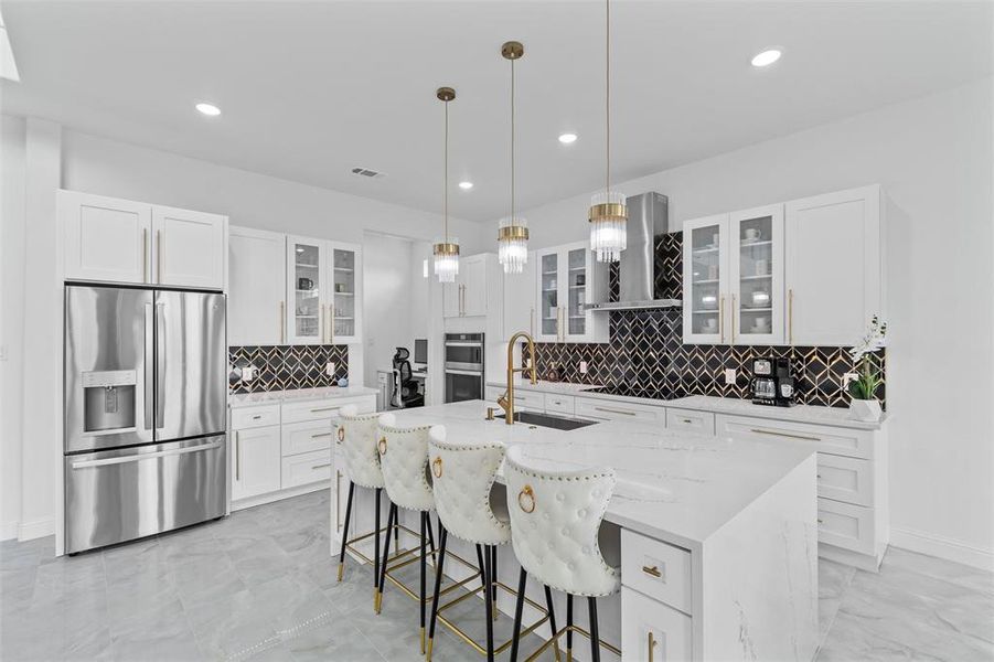 Modern kitchen featuring a large central island with seating, white shaker cabinetry, stainless steel appliances, a black and white geometric tile backsplash, and recessed lighting