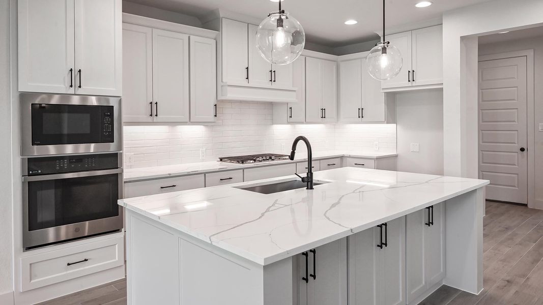 Unfurnished living room featuring light wood-style flooring, a fireplace, a towering ceiling, a sink, and recessed lighting