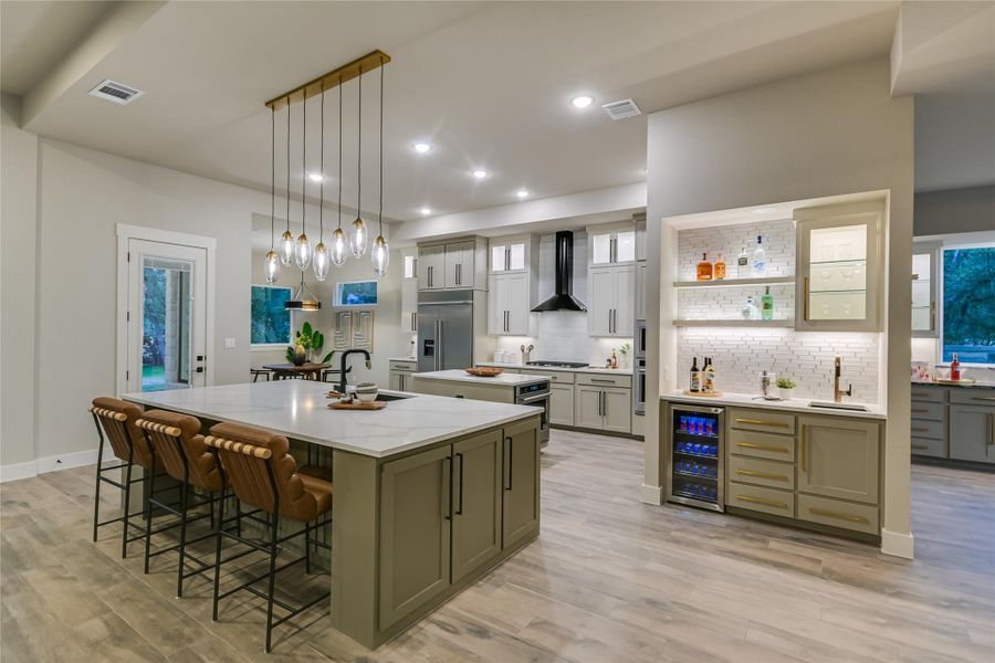 Kitchen with backsplash, a breakfast bar, beverage cooler, pendant lighting, and recessed lighting Kitchen with backsplash, a breakfast bar, beverage cooler, pendant lighting, and recessed lighting