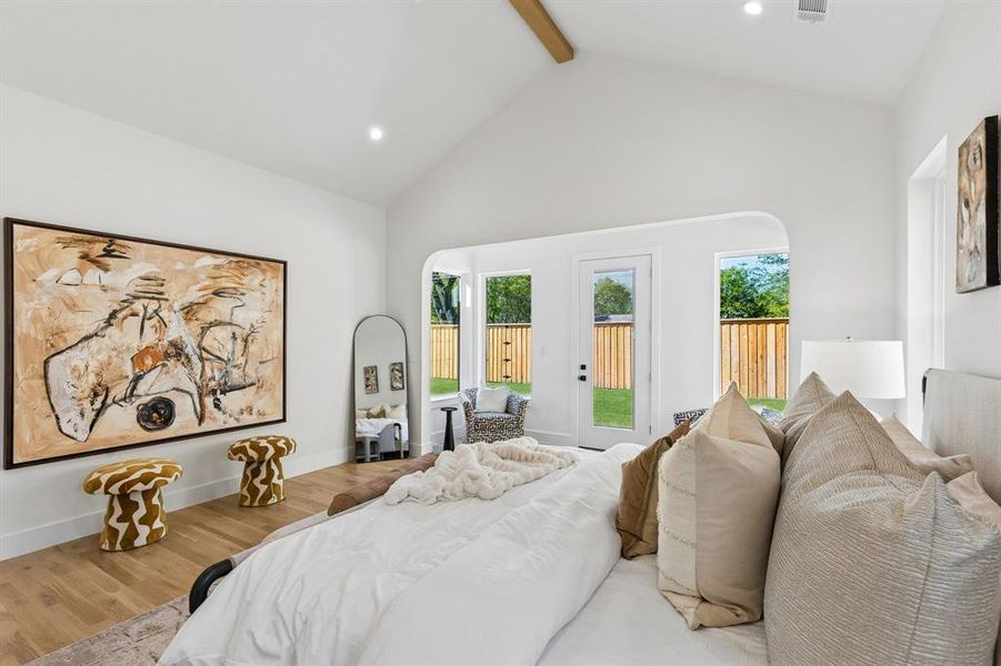 Bedroom with wood finished floors, access to exterior, recessed lighting, and arched walkways