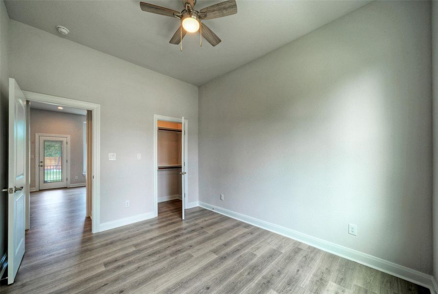 Unfurnished bedroom featuring light wood finished floors, a walk in closet, and a ceiling fan Unfurnished bedroom featuring light wood finished floors, a walk in closet, and a ceiling fan