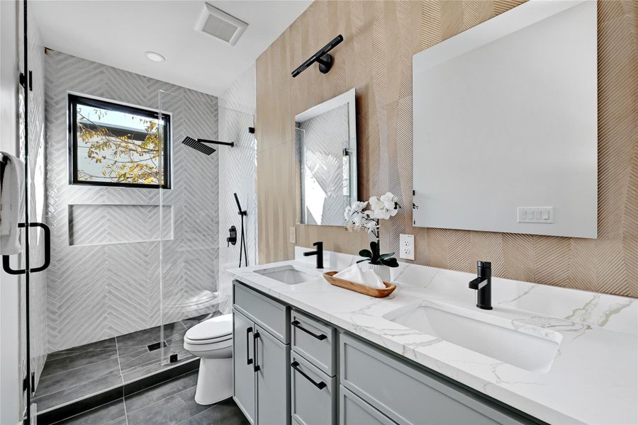 Bathroom with a stall shower, double vanity, wallpapered walls, dark tile patterned flooring, and recessed lighting