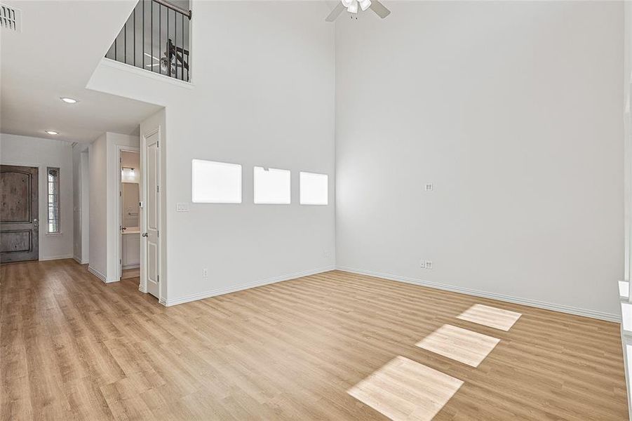 Unfurnished room with a high ceiling, light wood-type flooring, ceiling fan, plenty of natural light, and recessed lighting