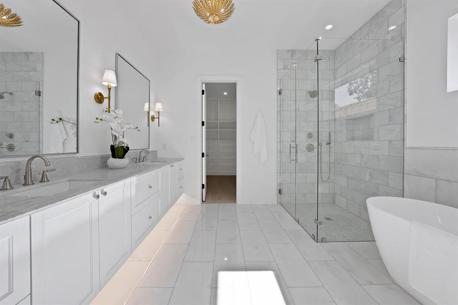 Spacious bathroom featuring a dual vanity with undermount sinks and stone countertops, a large glass-enclosed shower with tile surround, a freestanding soaking tub, and tile flooring