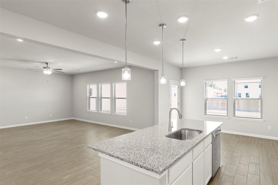 Kitchen with a sink, dishwasher, light wood-style floors, baseboards, and recessed lighting
