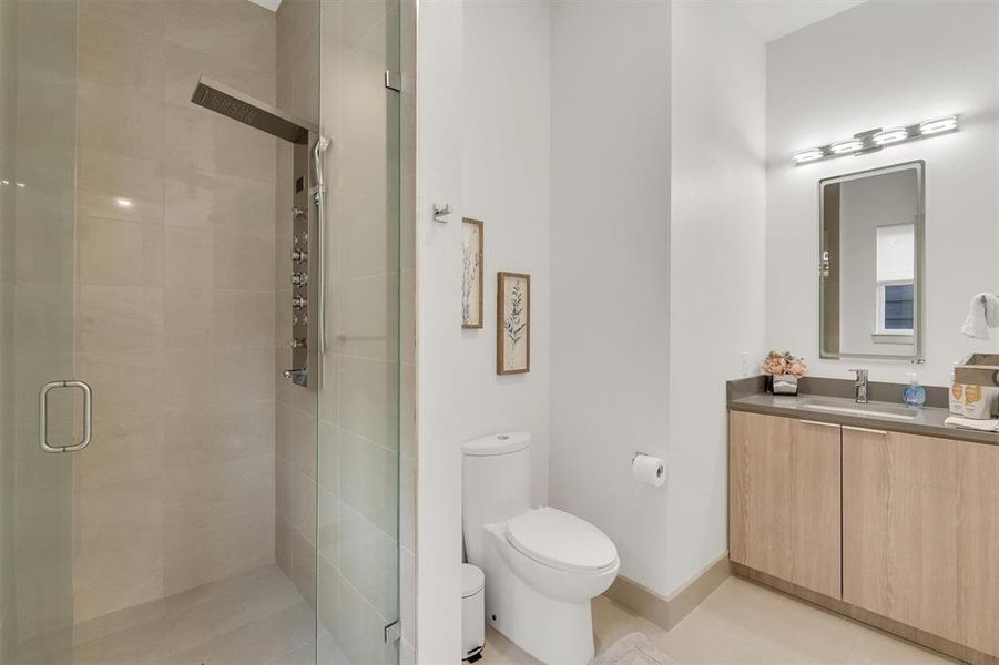 Bathroom featuring a shower with door, tile patterned floors, vanity, and toilet