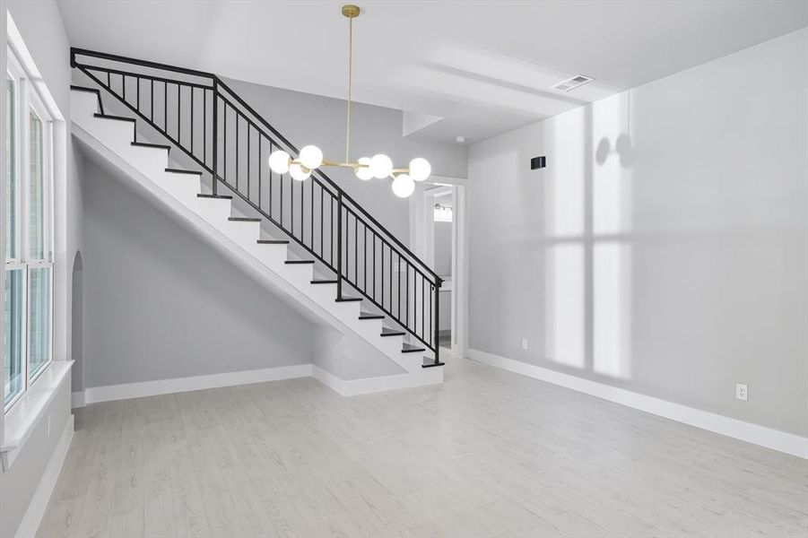 Foyer featuring light wood finished floors, a chandelier, and stairway