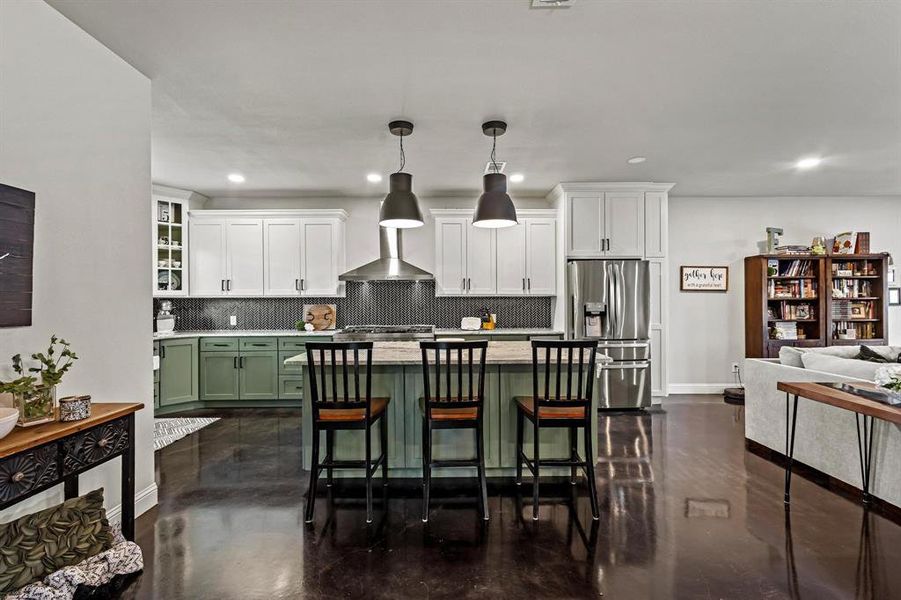 Kitchen featuring green cabinetry, tasteful backsplash, a breakfast bar, white cabinets, and stainless steel refrigerator with ice dispenser Kitchen featuring green cabinetry, tasteful backsplash, a breakfast bar, white cabinets, and stainless steel refrigerator with ice dispenser