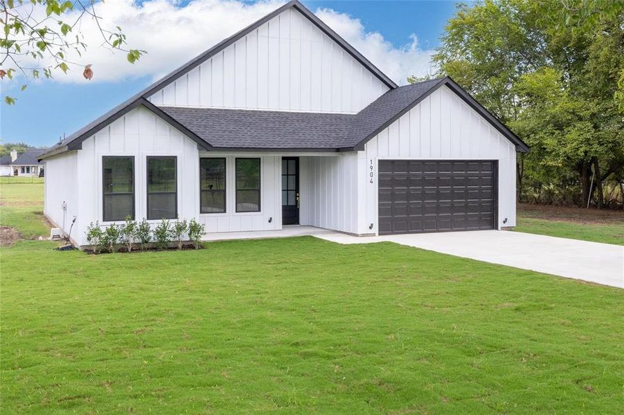 Modern farmhouse style home with a front yard and a garage